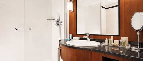 A modern bathroom with a white sink, a large mirror, and a shower area.