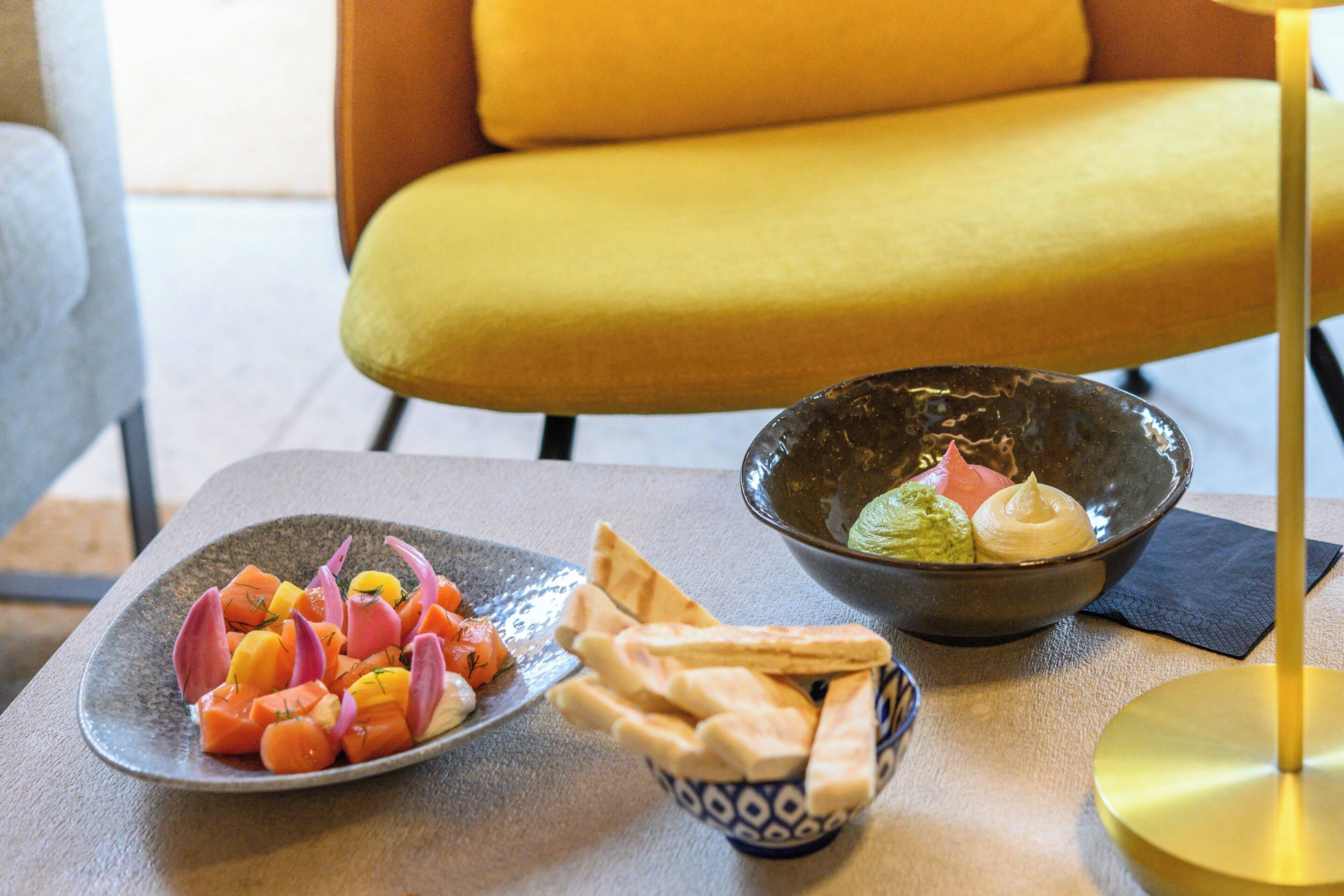 A dining table with a plate of food, a bowl of guacamole, and pita bread.