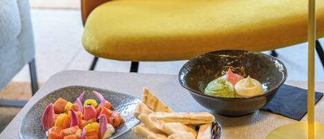 A dining table with a plate of food, a bowl of guacamole, and pita bread.