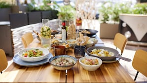 Una mesa de comedor con varios platos, vasos y una botella, rodeada de sillas.
