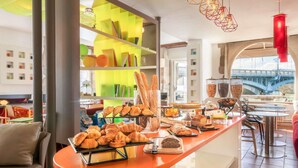 Un comptoir où l’on sert le petit-déjeuner avec des viennoiseries, une vue sur un pont et un décor intérieur moderne.