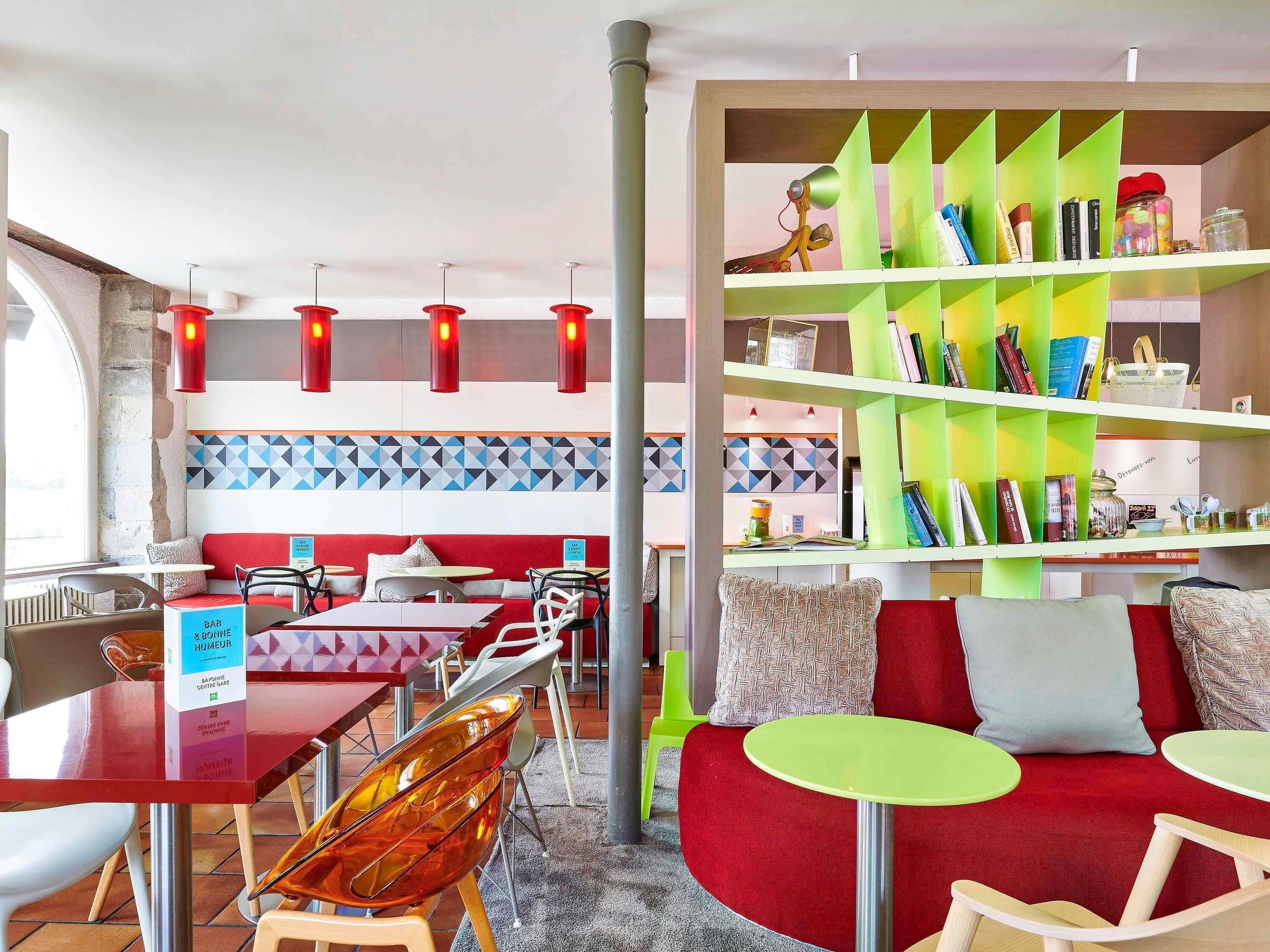 A modern interior with red seating, green and white shelves, and red pendant lights.