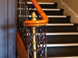 Una escalera con barandilla de madera y balaustres de metal.
