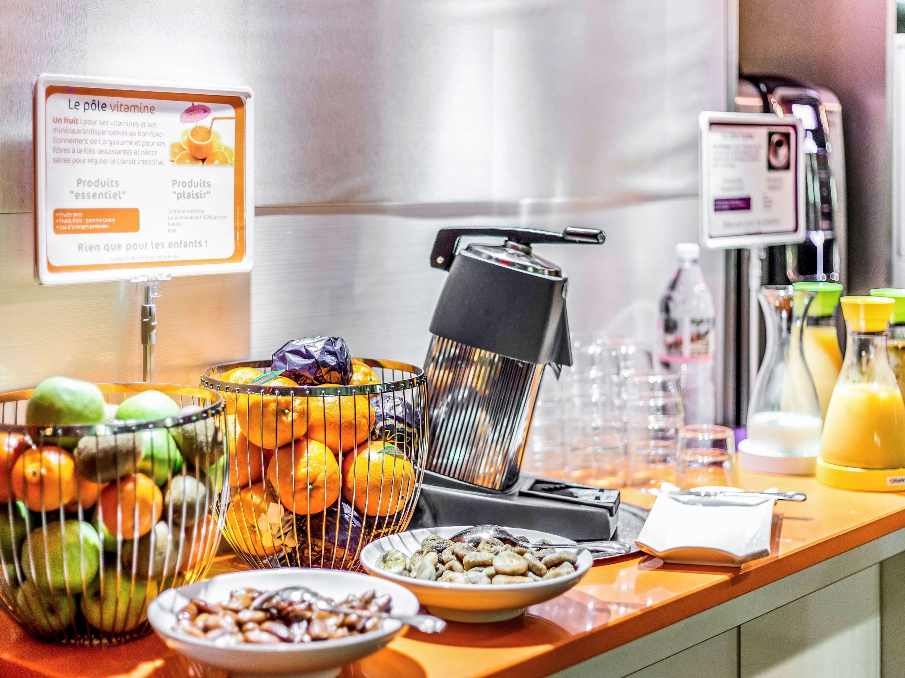 A breakfast buffet with fruits, cereals, and juice dispensers.