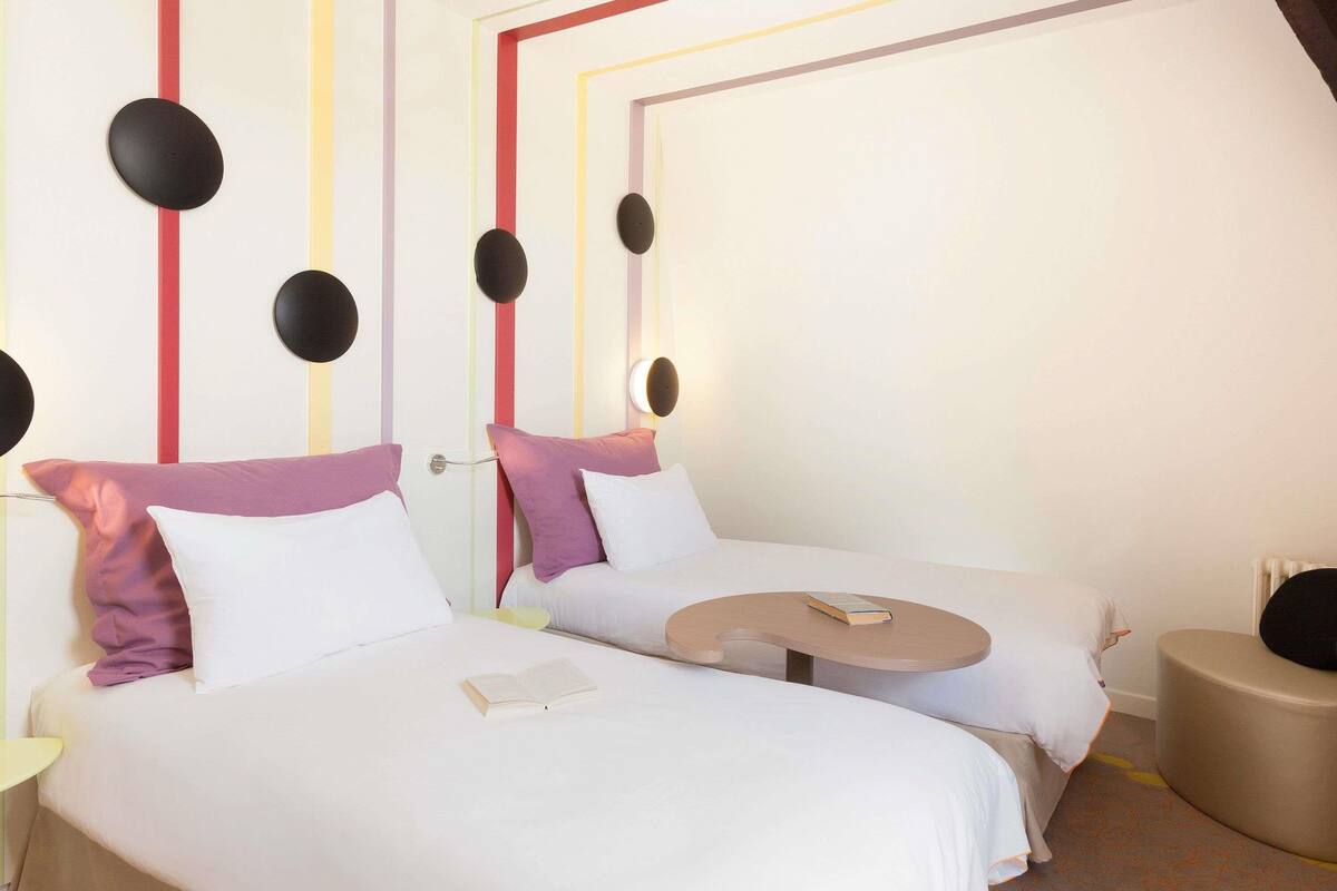 Una habitación de hotel con dos camas, una mesita y un área de descanso circular.