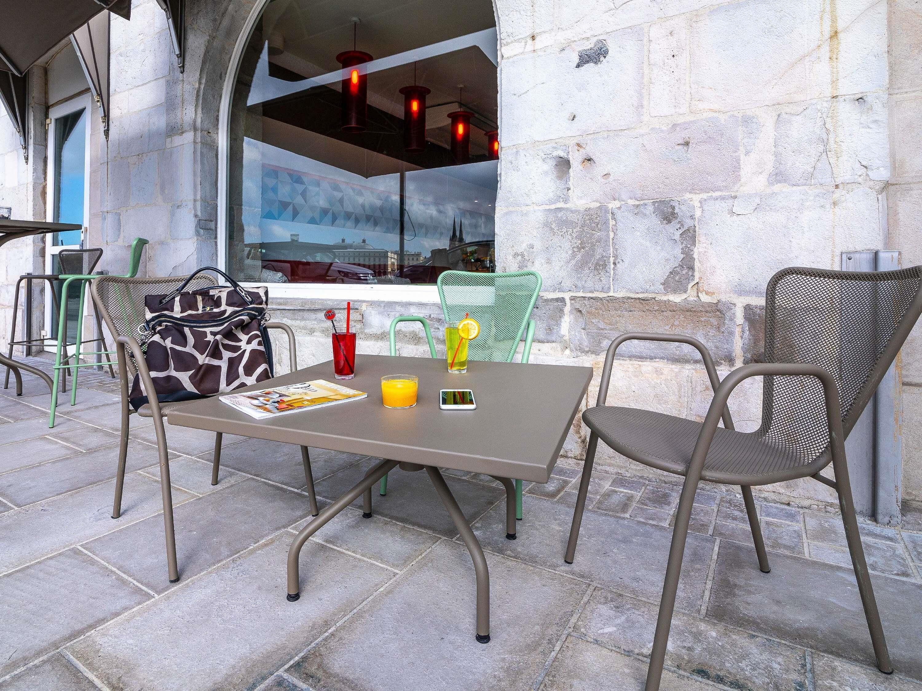 An outdoor seating area with a table, chairs, and a view of the street.