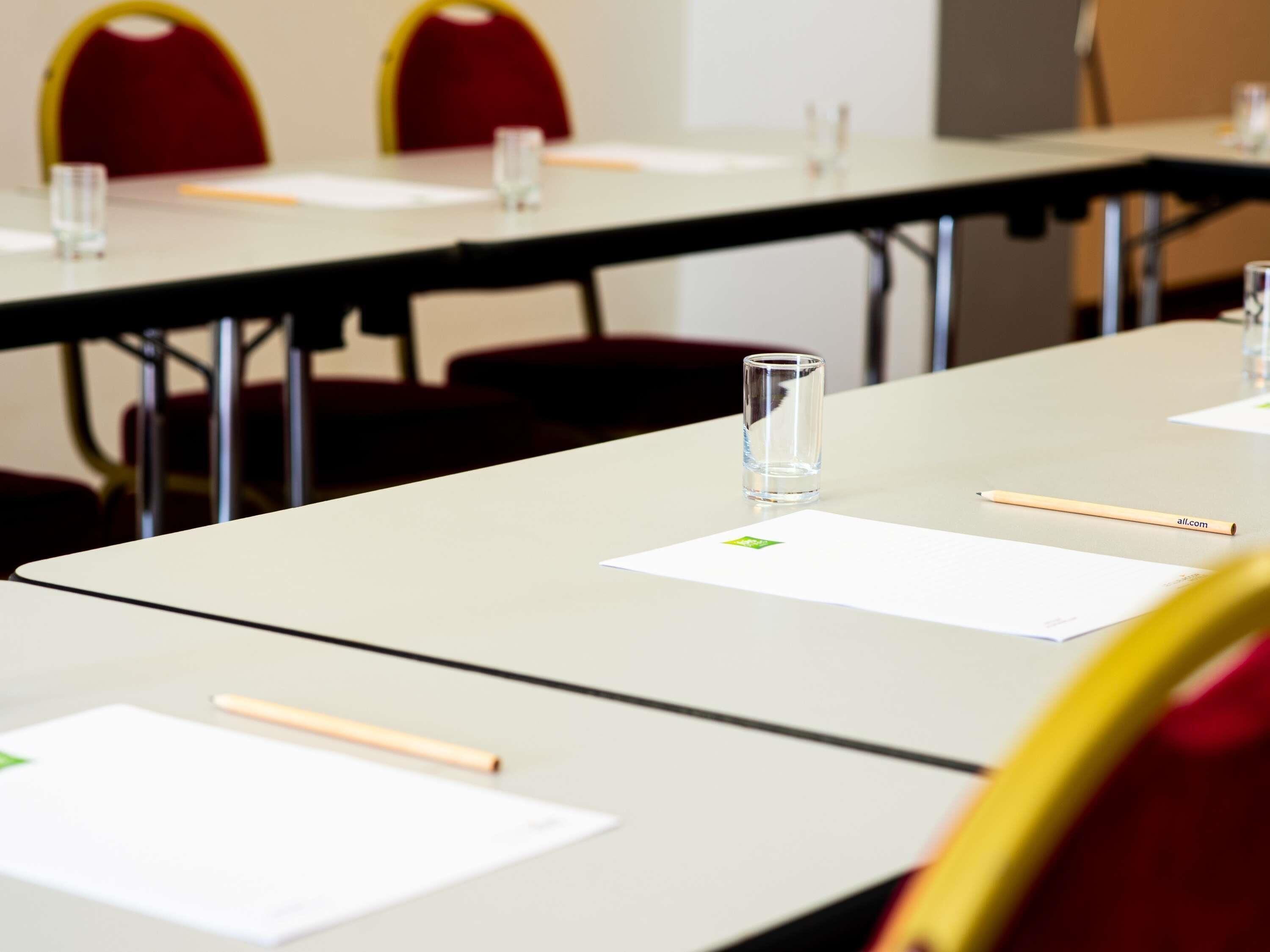 A conference room with tables, chairs, and documents.