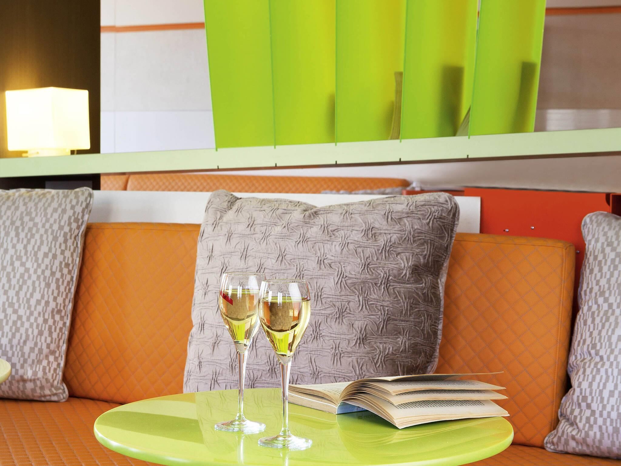 A green table with two glasses of wine and an open book.
