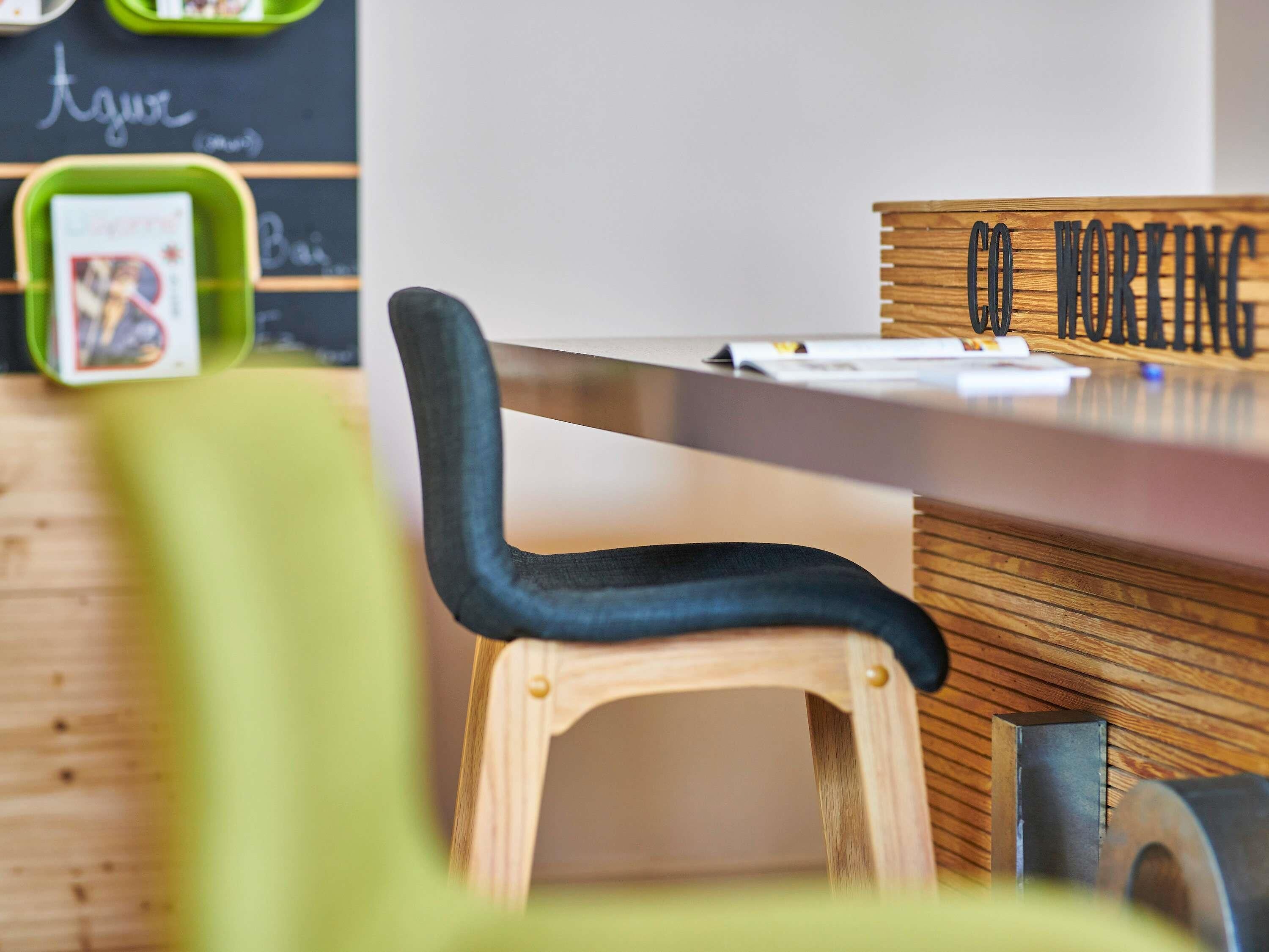 Uma mesa de madeira com uma placa que diz 'CO WORKING' e uma lousa com a palavra 'Agur' escrita.