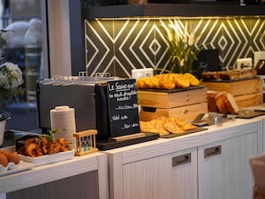 A buffet counter with a chalkboard menu, various food items, and a coffee machine. - Novotel La Grande Motte Golf (La Grande-Motte)