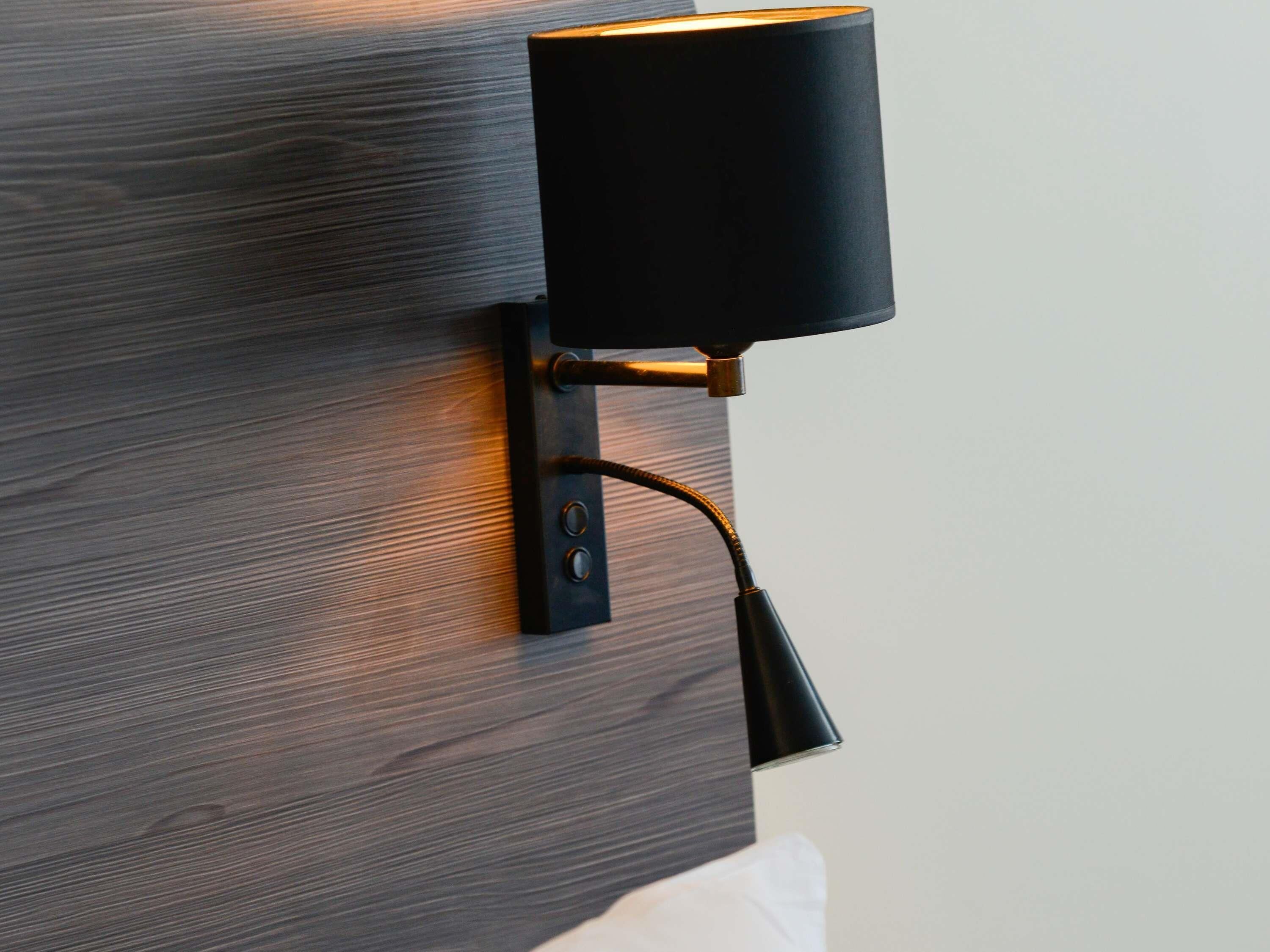 A wall-mounted lamp with a cord, attached to a wooden wall.