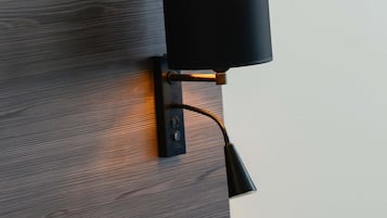 A wall-mounted lamp with a cord, attached to a wooden wall.