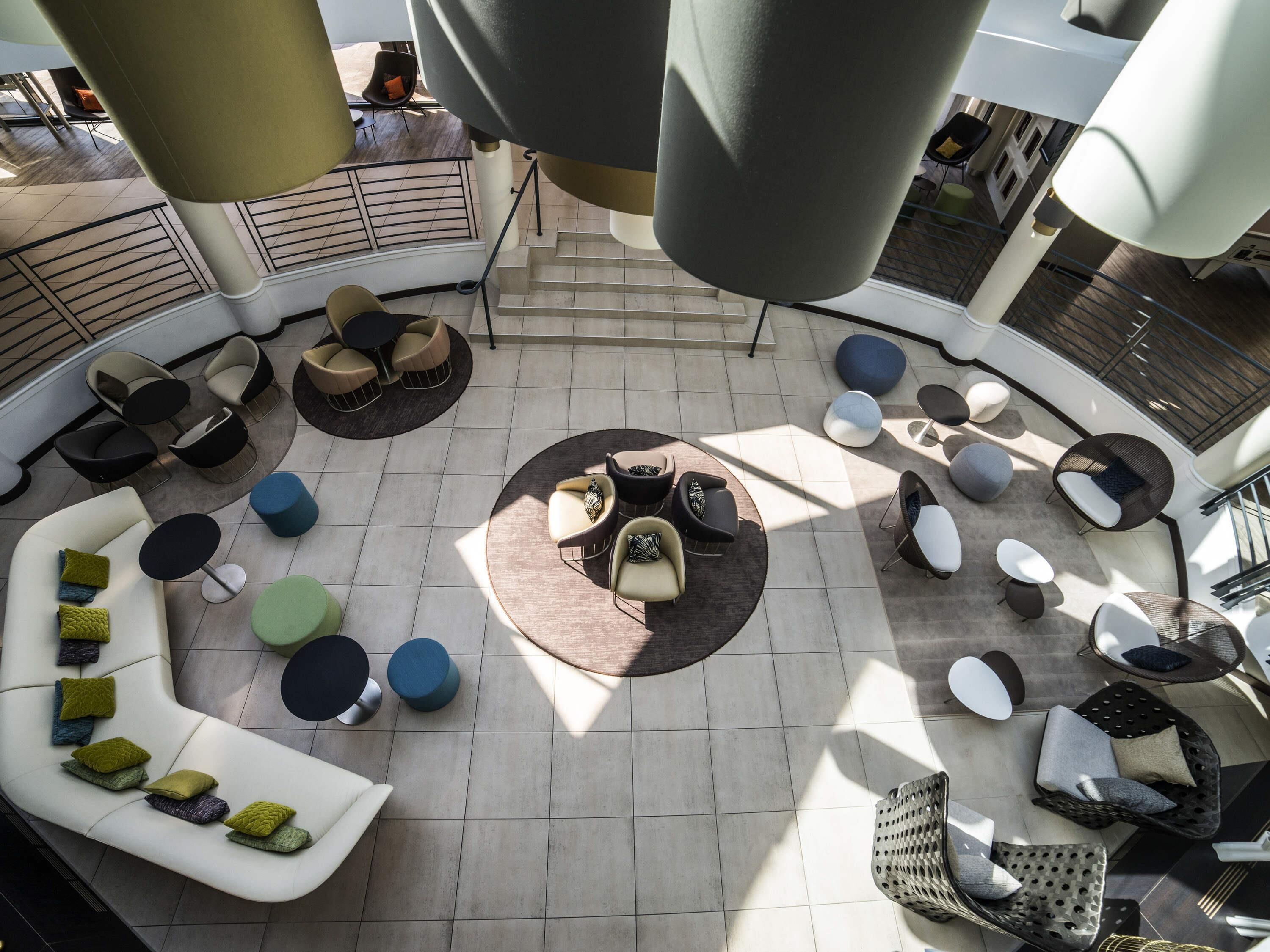 A spacious indoor area with a central seating arrangement, a staircase, and a railing.