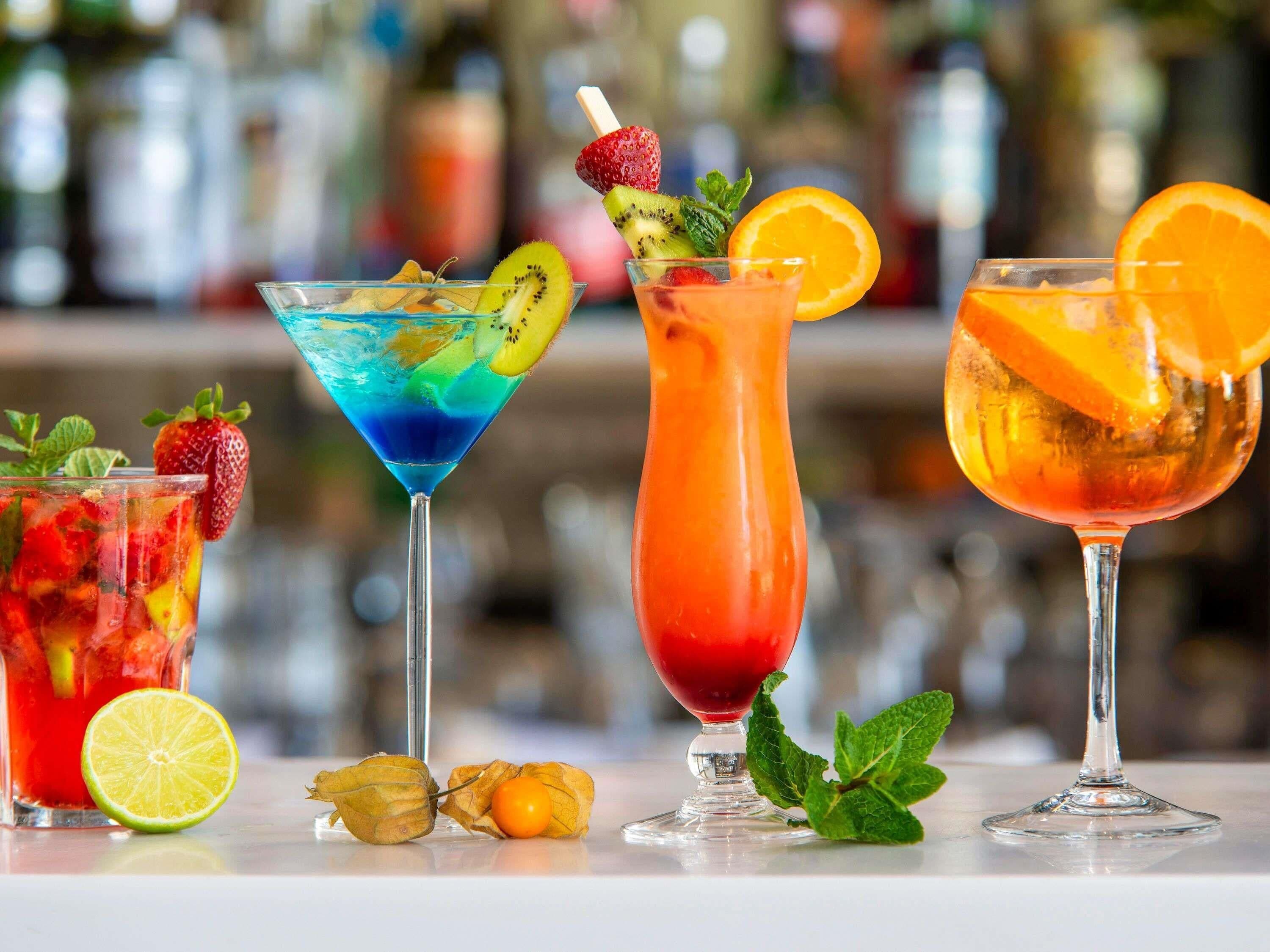 Fyra olika cocktails med olika sorters frukt och garnering.