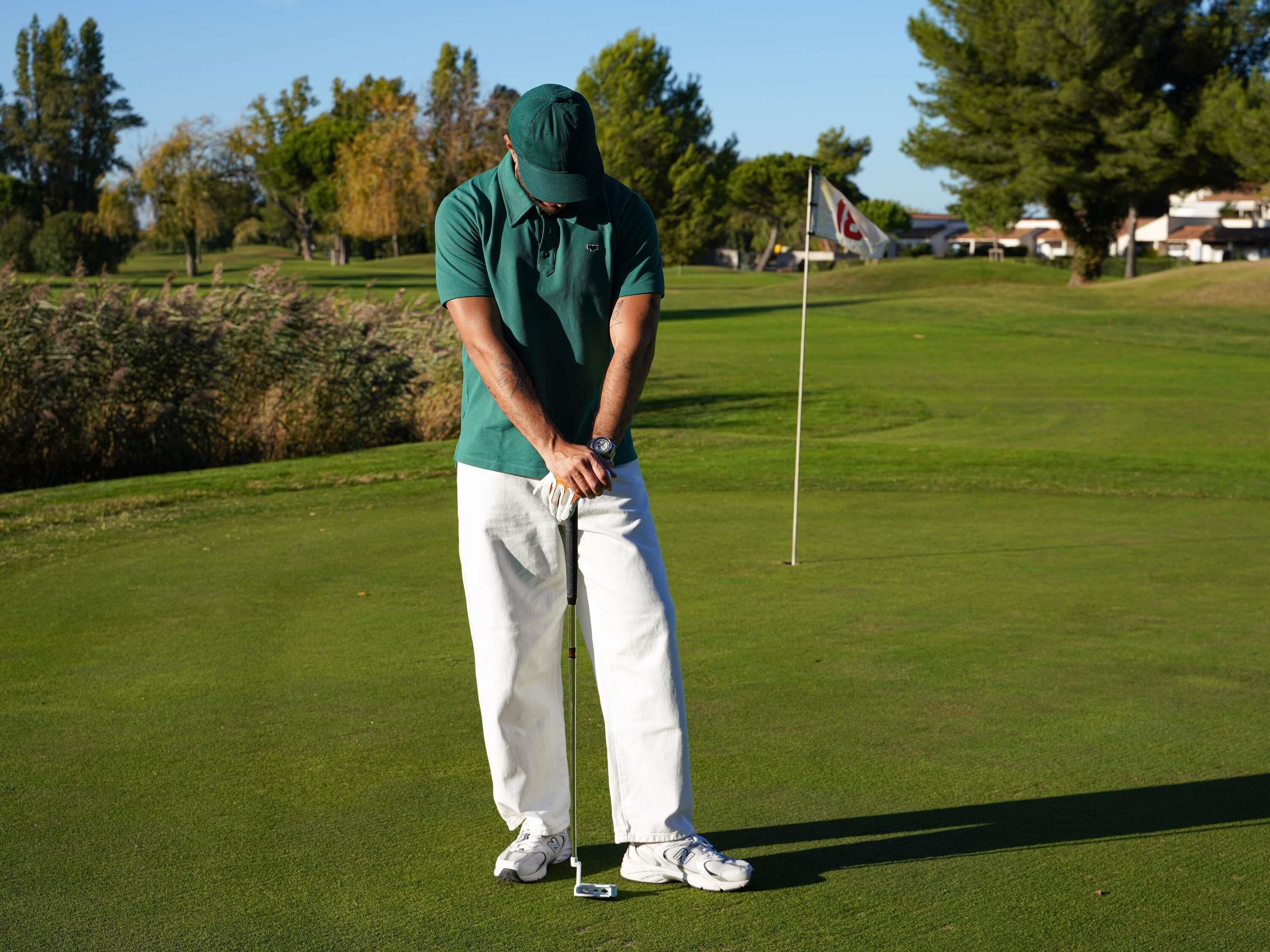 Une personne sur un terrain de golf, avec un mât de drapeau en arrière-plan.