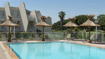 Una piscina al aire libre de temporada, sombrillas