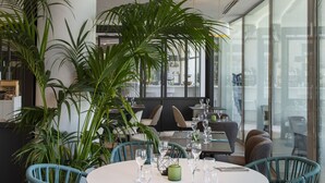 Un espace de salle à manger moderne avec une table ronde, des chaises bleues et des luminaires suspendus.
