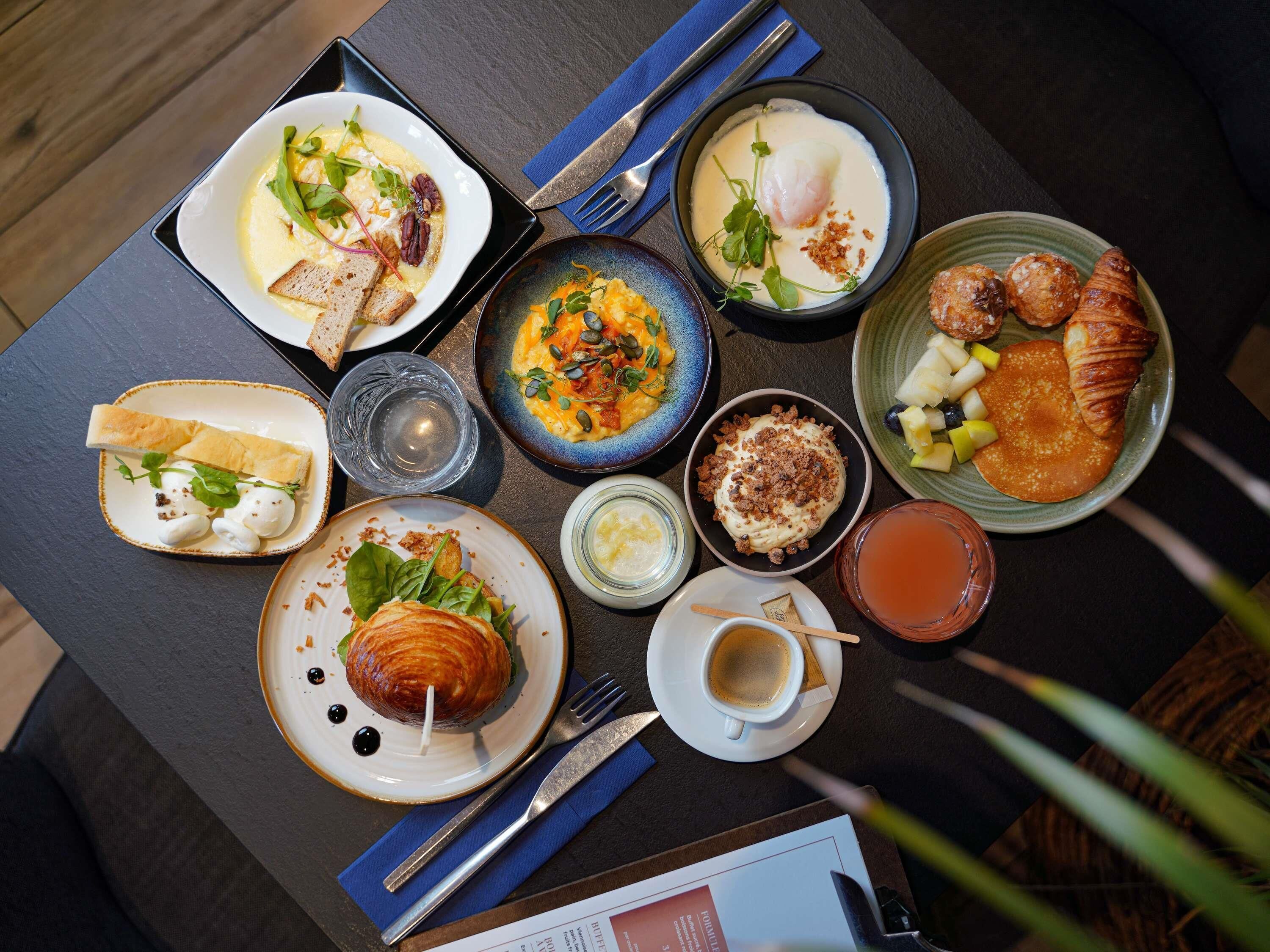 Variedad de platillos de desayuno sobre una mesa con cubiertos y un menú.