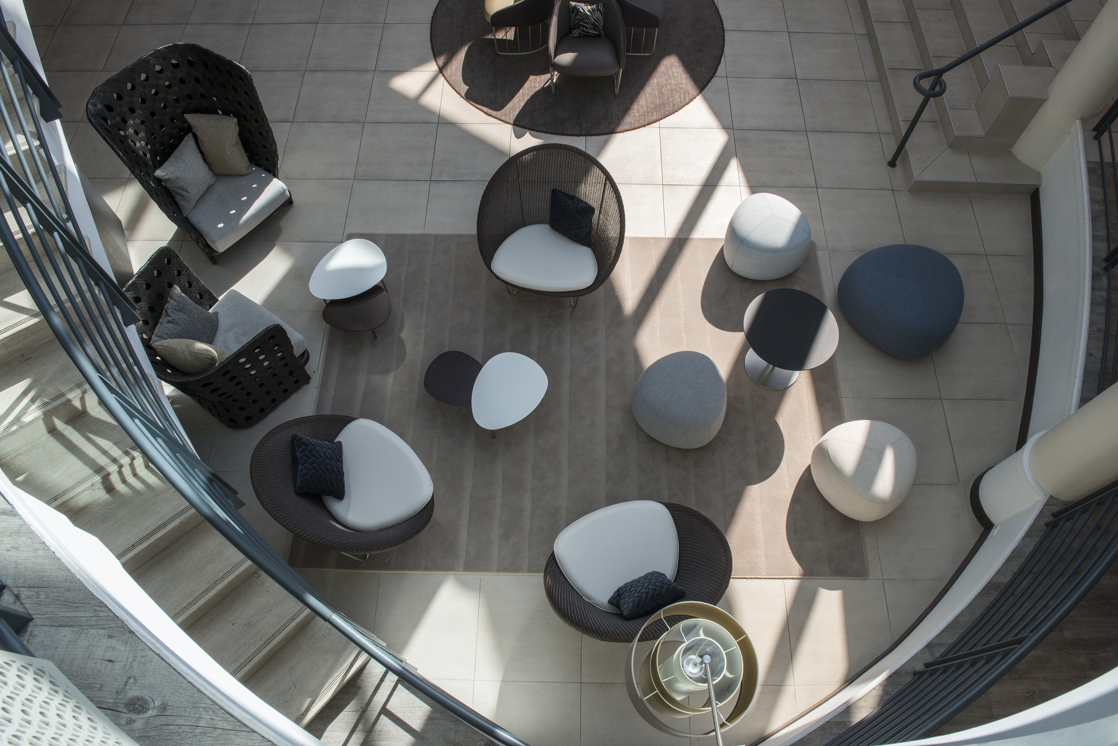 Un área de estar al aire libre moderna con sillones redondos y rectangulares, una mesa de centro y una escalera en espiral.
