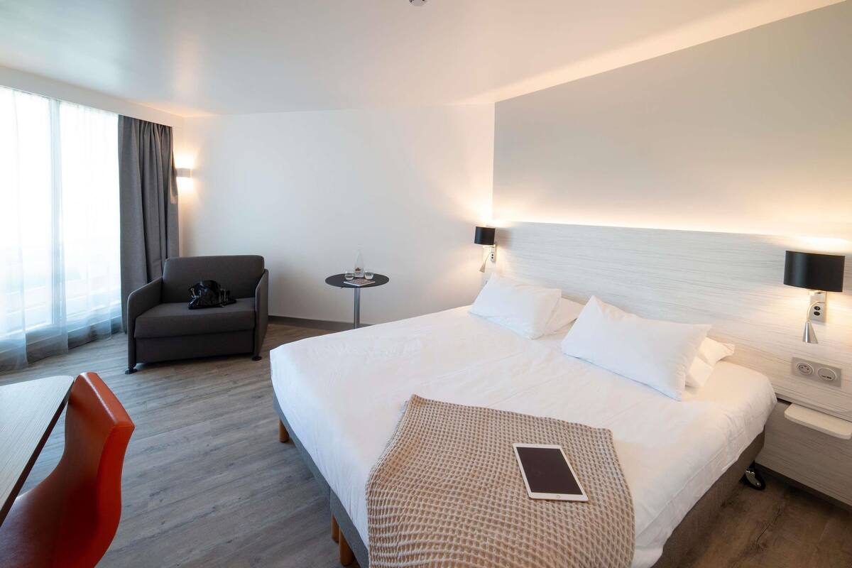 Ein Hotelzimmer mit einem großen Bett, einer Couch, einem kleinen Tisch und einem Sessel.