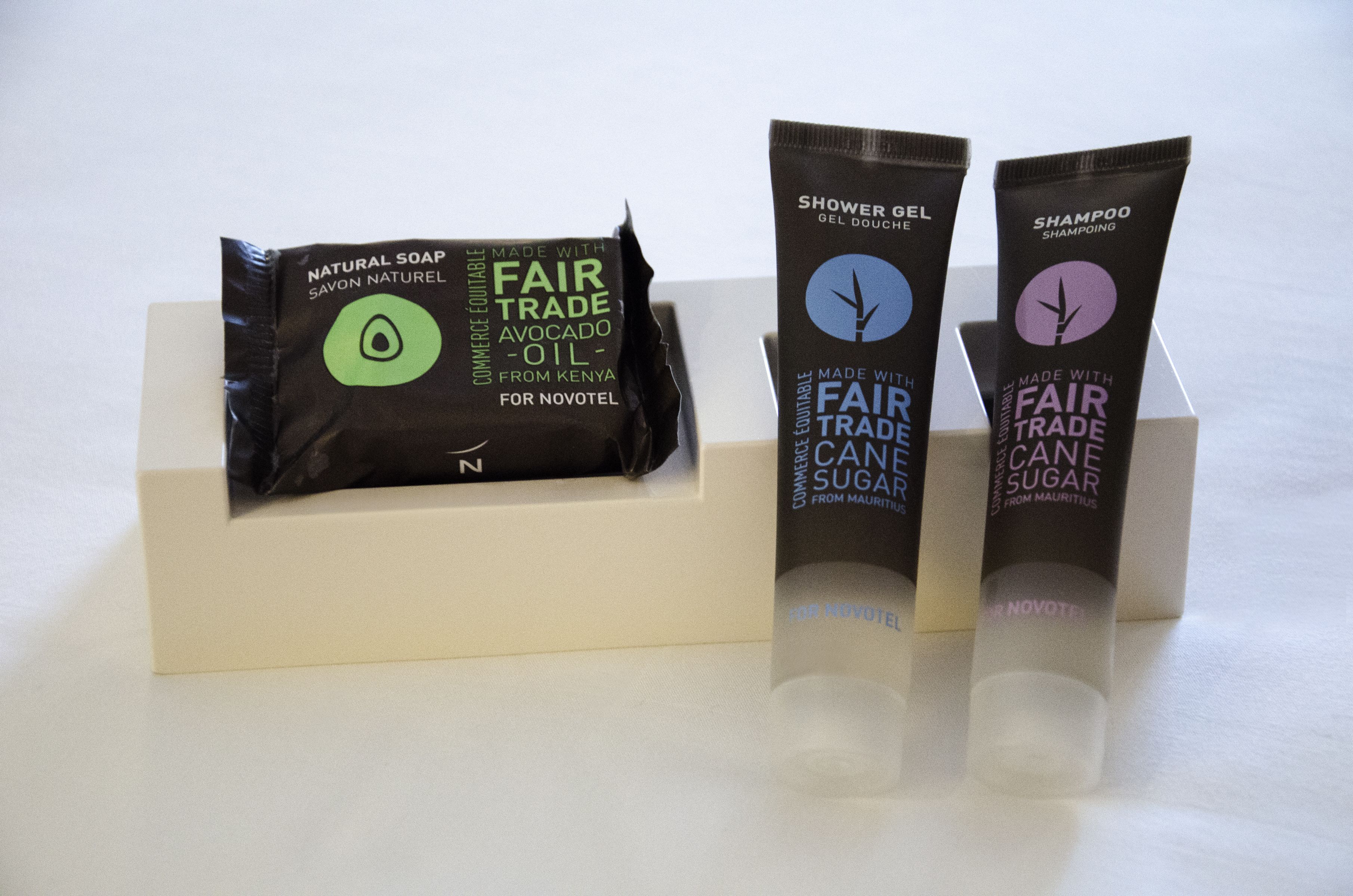 Three toiletries in a hotel display: natural soap, shower gel, and shampoo.