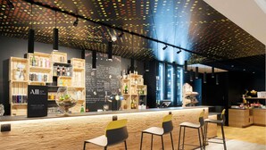 Eine Bar mit einer Holztresen, Barhocker und Regalen voller Flaschen.