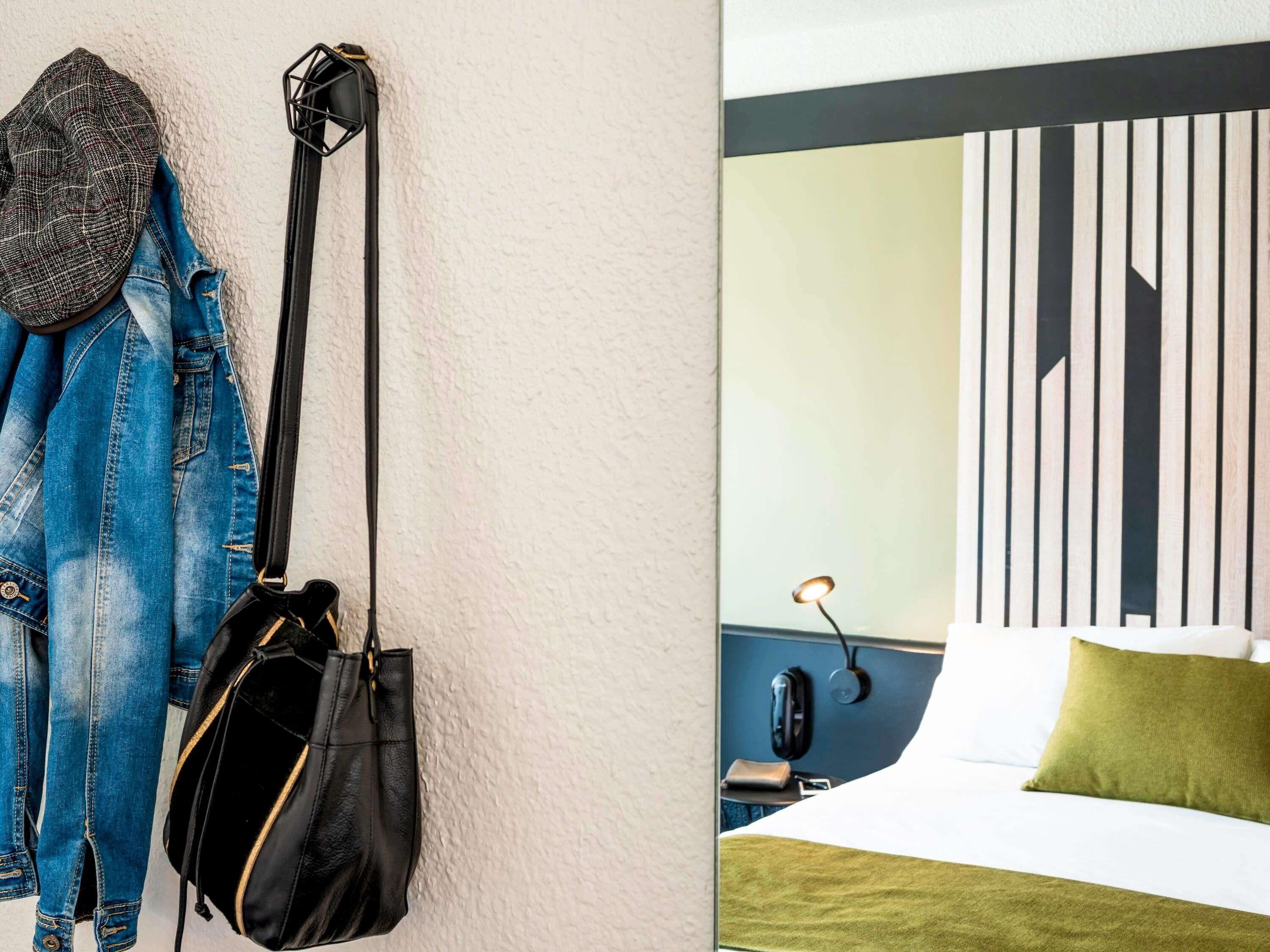 Et hotelværelse med en seng, et natbord, en lampe og en væg med lodrette linjer.