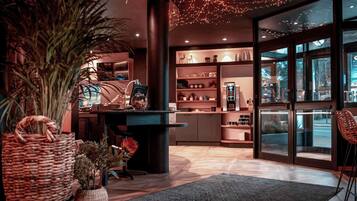 A modern interior with a central column, shelves with various items, a large plant, and a view through a glass door.