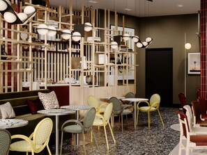 A modern cafe interior with round tables, yellow and white chairs, and a wooden bookshelf with various items. - TRIBE Strasbourg Centre Gare (Strasbourg)