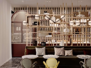 A modern interior with a sofa, patterned cushions, and a decorative wall with shelves. - TRIBE Strasbourg Centre Gare (Strasbourg)