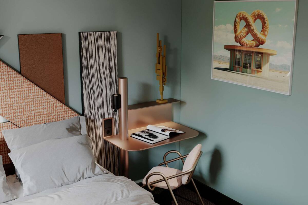 A bedroom with a bed, a small desk with a chair, a bookshelf, and a wall-mounted artwork of a pretzel.