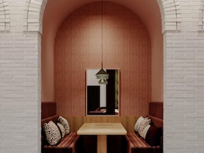 A room with a brick wall, a wooden table, and two cushioned seating areas.