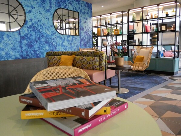 Un área de descanso moderna con un sofá, un sillón de mimbre y una mesita con libros.