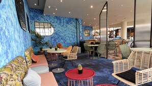 A modern lounge area with a blue textured wall, wicker furniture, and a central seating area with a round table.