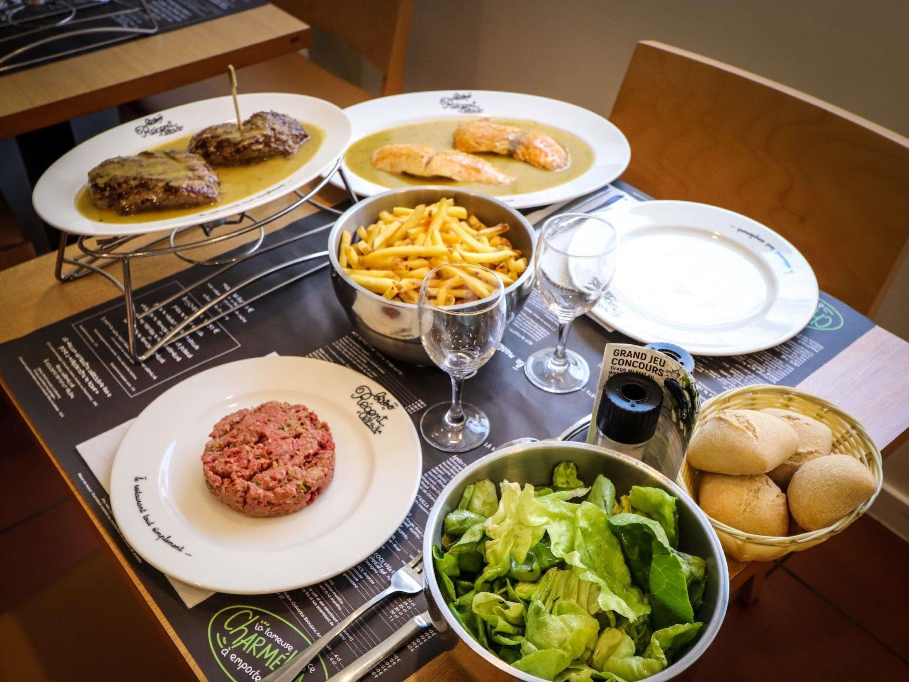 A table set with various dishes, including meat, fish, fries, and bread.