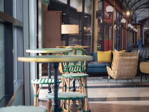 A modern interior with wicker furniture, including chairs and tables, and a blue sofa in a well-lit area with large windows. - ibis Styles Evry Courcouronnes Hotel and Events (Évry-Courcouronnes)