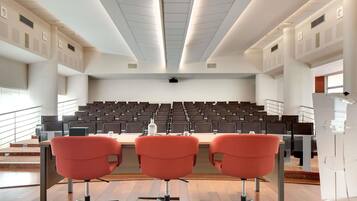 A conference room with rows of chairs, a podium, and a projector screen.