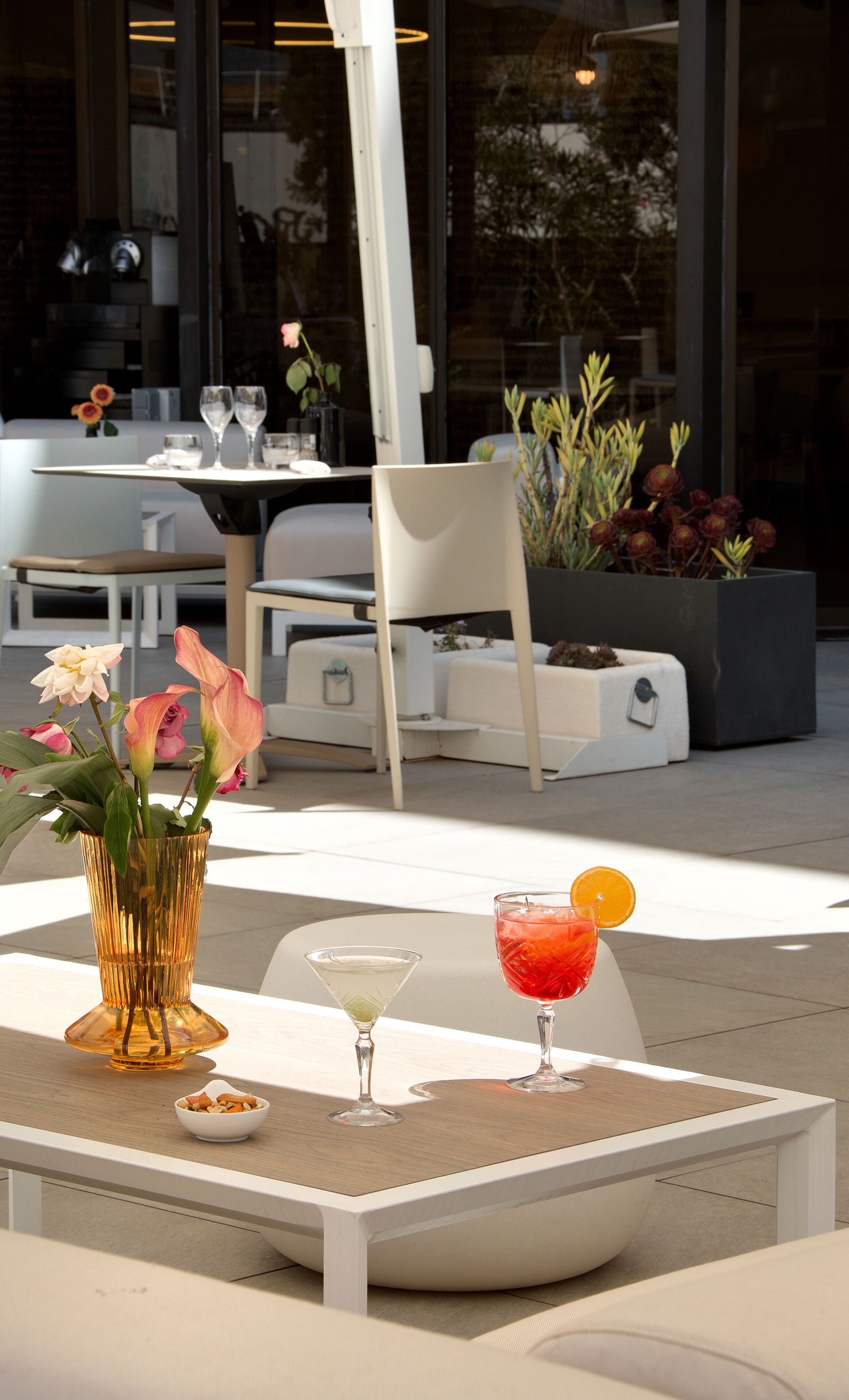Un espace extérieur moderne aménagé avec une table, des chaises et un pot de fleurs.