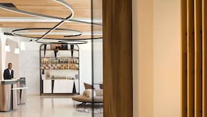 Un hall d’hôtel moderne comprenant un comptoir d’accueil, un espace salon et un présentoir présentant les différents services proposés.