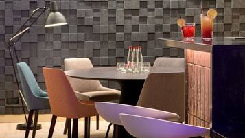 A modern dining area with a round table, chairs, a bar counter, and a wall with a geometric pattern.