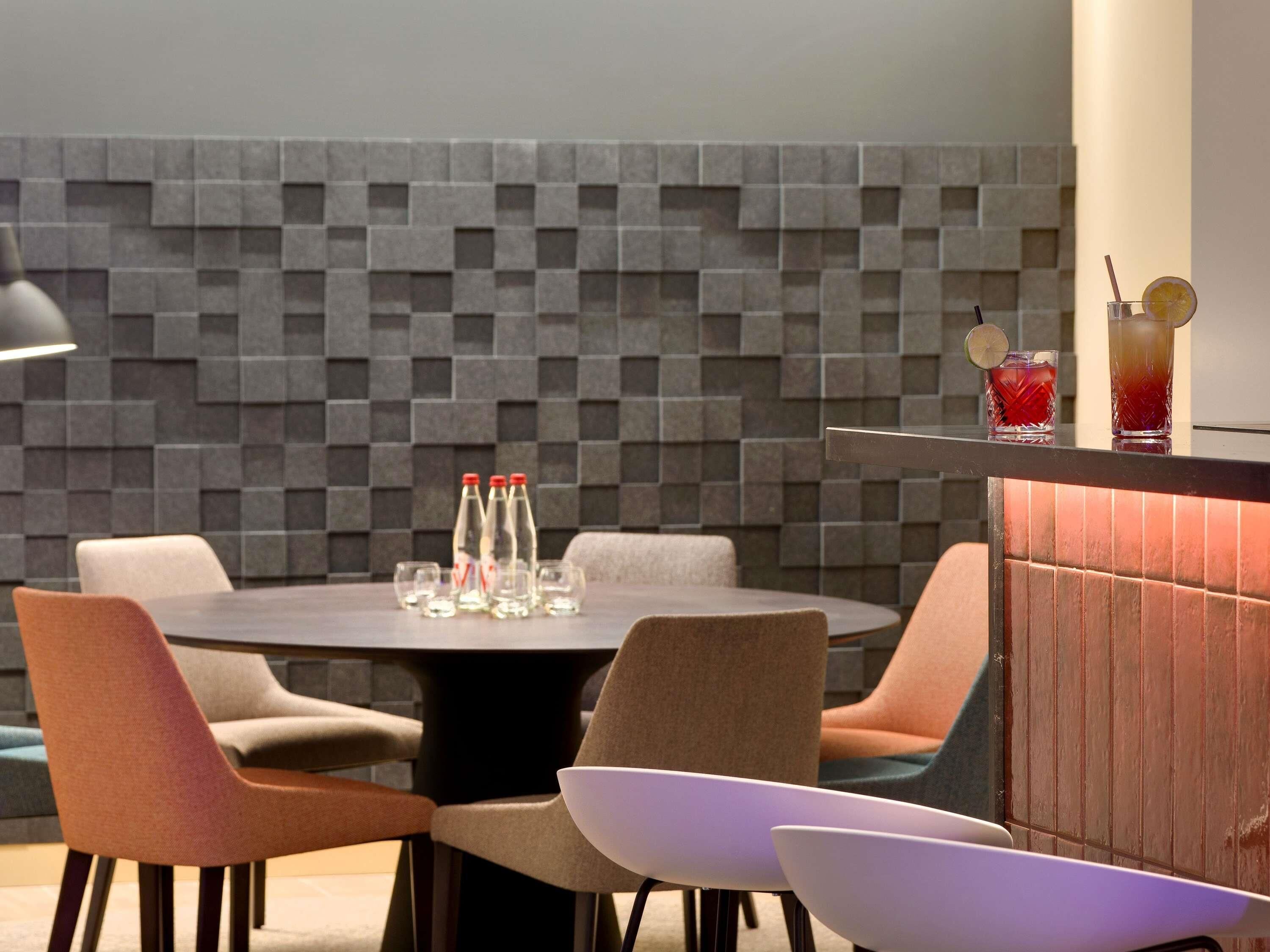 Ein moderner Essbereich mit einem runden Tisch, gepolsterten Stühlen und einer Bar mit Gläsern und Flaschen.