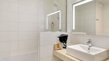 A modern bathroom with a white sink, a mirror, and a shower.