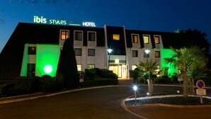 Un hotel moderno con un cartel que dice "ibis Styles Hotel" de noche.