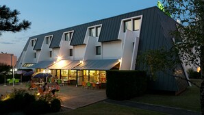Un hotel moderno con un diseño arquitectónico único, que presenta un techo inclinado y grandes ventanales.