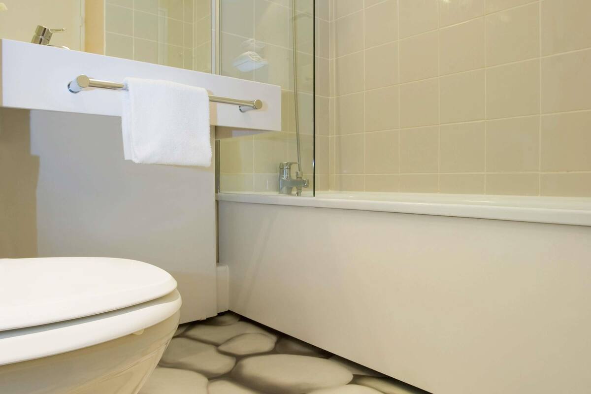 Ein modernes Badezimmer mit Toilette, einer Duschkabine aus Glas und Fliesenboden.