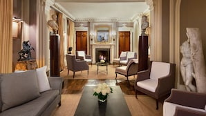 A formal sitting room with a fireplace, classical statues, and a modern sofa. - Le Dokhan’s Paris Arc de Triomphe, a Tribute Portfolio Hotel (Paris)