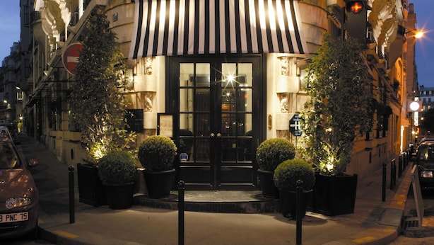 A historic building with a classic facade, a black iron balcony, and a black and white striped awning. - Le Dokhan’s Paris Arc de Triomphe, a Tribute Portfolio Hotel (Paris)