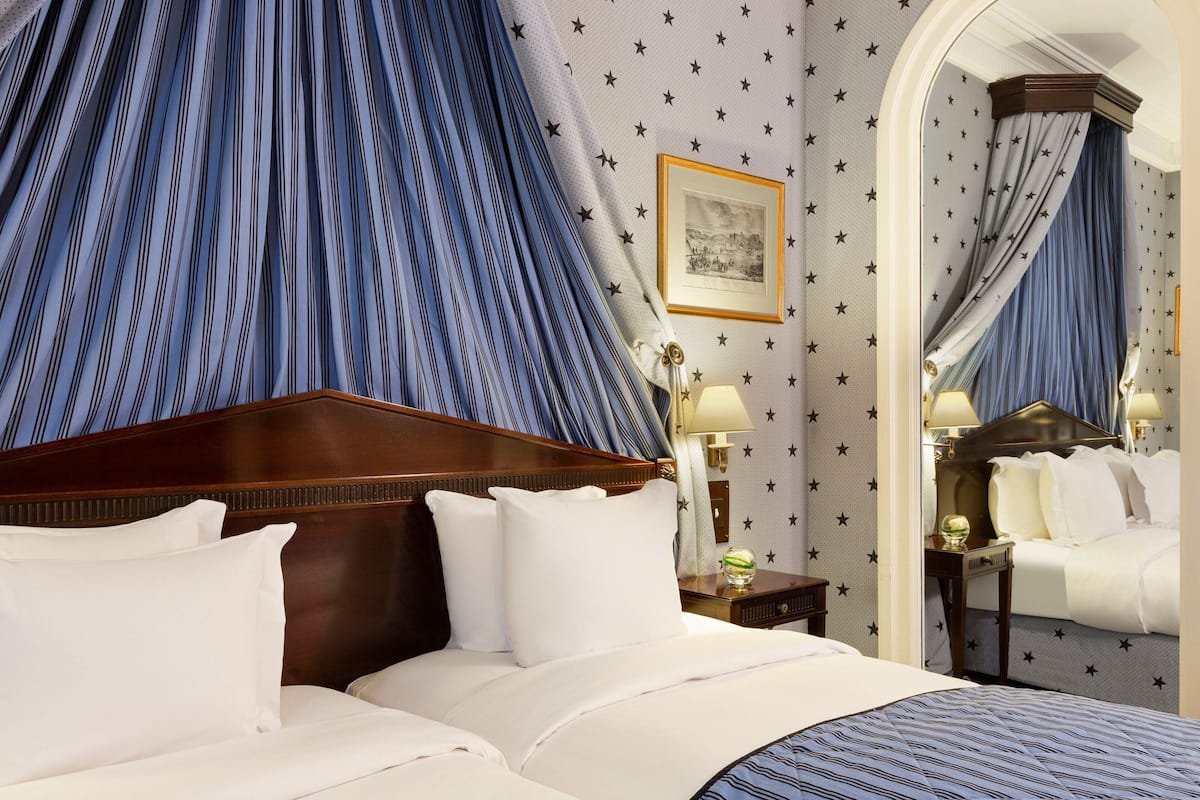 Ein Hotelzimmer mit einem großen Bett, einem Holzkopfteil, einem Nachttisch mit Lampe und einem Spiegel.
