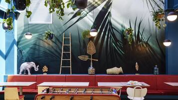 Relax in a vibrant space with a unique wooden table and lush greenery, surrounded by a tropical mural.