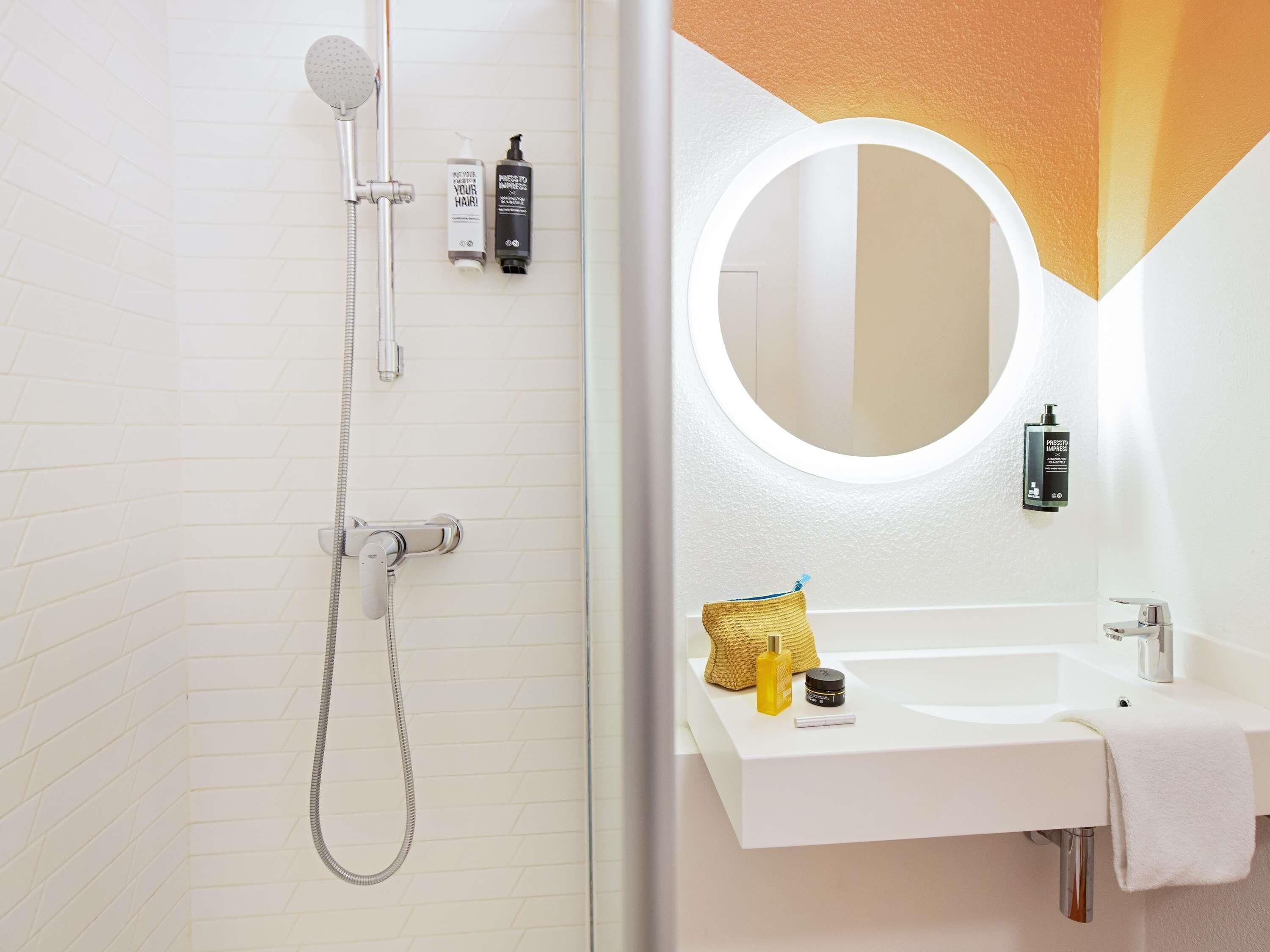 A modern bathroom with a shower, a sink, and a mirror.
